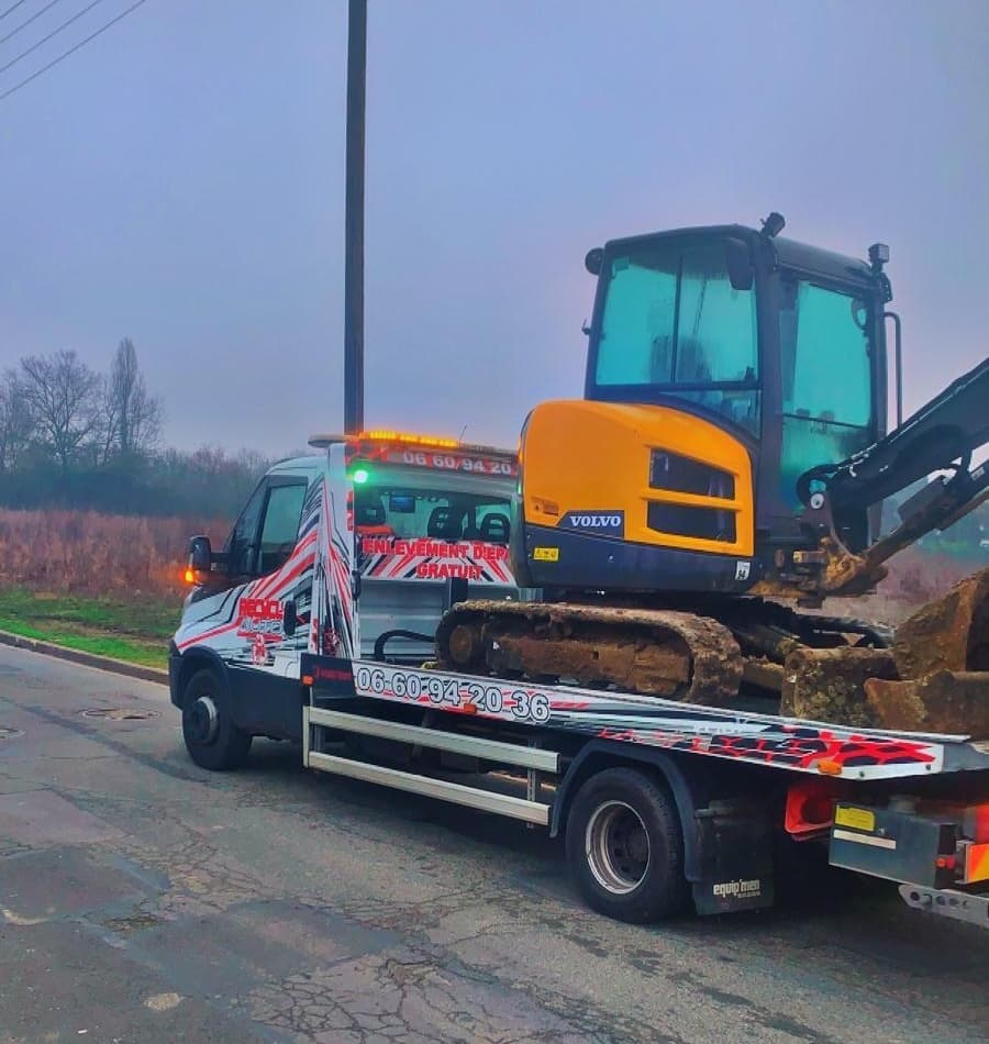 Dépannage : camion plateau transportant une mini-pelle